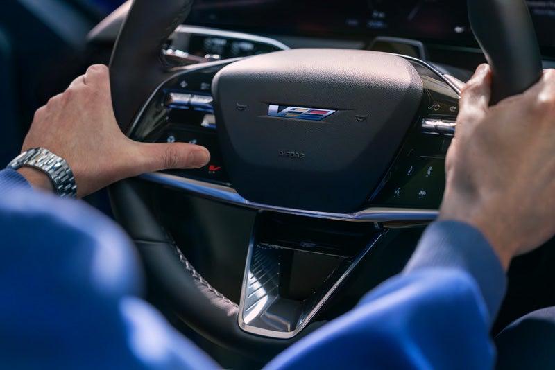 Close-up of a Man About to Press the V-Button on the 2026 OPTIQ-V Steering Wheel | Fairfield Cadillac in LEWISBURG PA