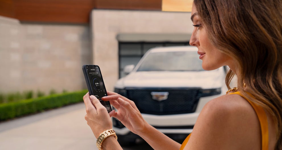 lady checking her mobile with a Cadillac vehicle background | Fairfield Cadillac in LEWISBURG PA